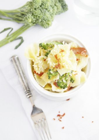 Cheesy Baked Pasta with Broccolini in white bowl. Fork and sprig of broccolini to side.
