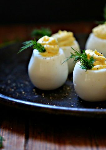 Deviled Eggs on brown plate garnished with dill