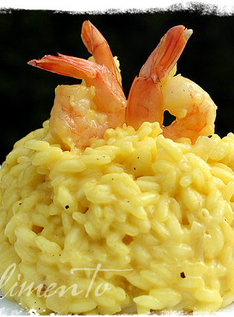 mound of saffron risotto with shrimp garnished on top.