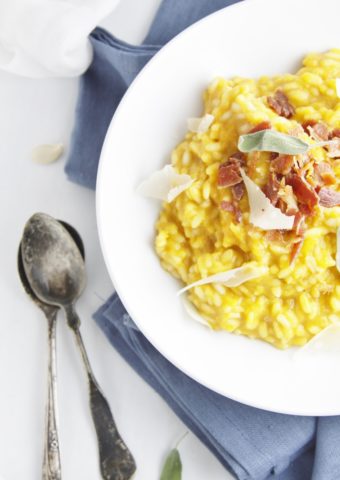 bowl of roasted pumpkin risotto with pancetta on blue napkin with spoons