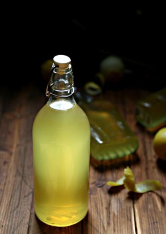 bottles of homemade limoncello with lemon peels surrounding