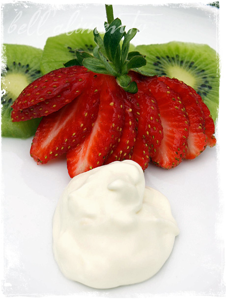 dollop of mascarpone on white plate with sliced strawberries and kiwi