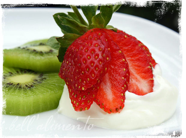homemade mascarpone dollop on white plate with slices of strawberries and kiwi.