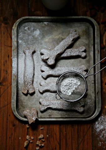 Bones of the Dead Cookies on baking sheet with sieve of powdered sugar above