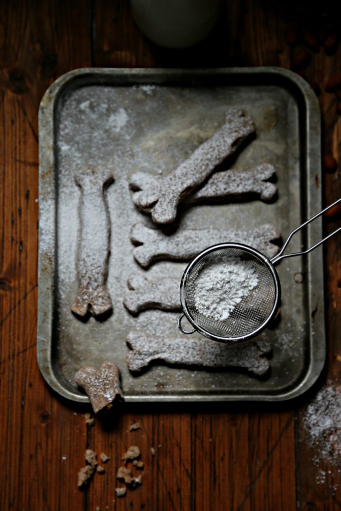 Bones of the Dead Cookies on baking sheet with sieve of powdered sugar above