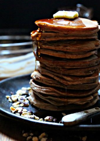 stack of Nutella pancakes on plate with batter bowl behind and butter
