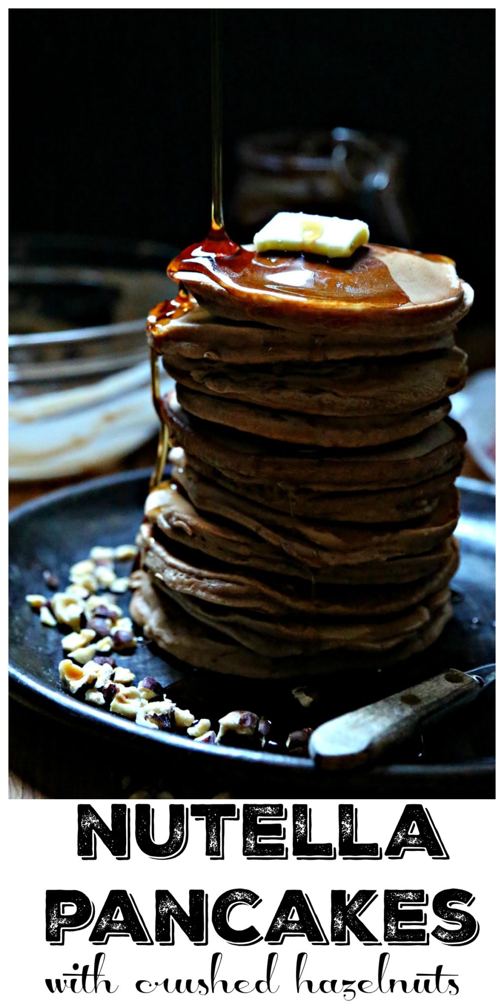 Pinterest Image. Stack of Nutella pancakes on plate with butter, syrup and crushed hazelnuts. Text overlay that reads Nutella Pancakes with crushed hazelnuts.