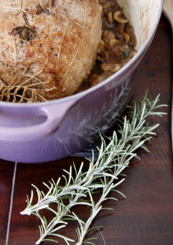 braised pork roast in cassis le creuset with fresh rosemary sprigs to side.