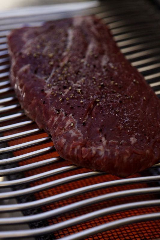 flank steak cooking on infrared grill. 