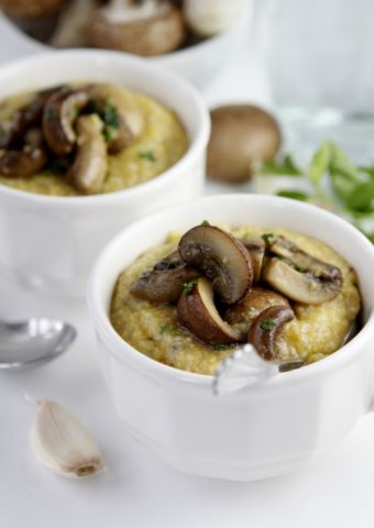 2 small white bowls of Creamy Polenta with Mushroom Sauce. Spoons to side.