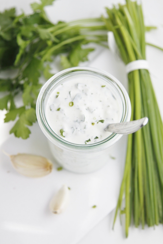 ranch dressing in small glass jar with spoon. Ingredients to side.