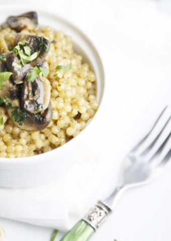 white bowl of Couscous with Mushrooms and Herbs. Fork to side.