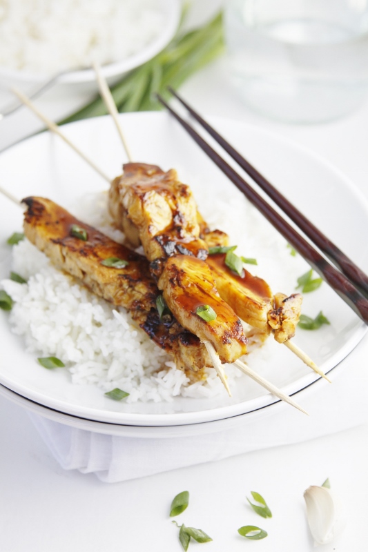 Chicken Yakitori skewers over Rice in a white bowl. Chop sticks to side.