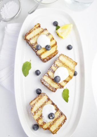 3 slices of grilled pound cake on white tray topped with yogurt and blueberries.