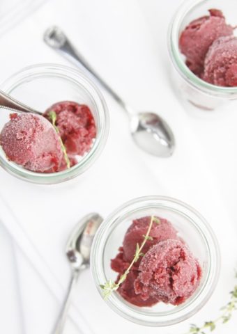 3 small glass jars filled with scoops of blueberry sorbet. Spoons scattered around.