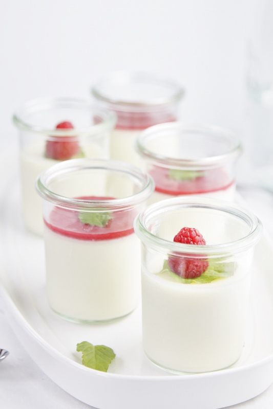 5 small glass jars of Raspberry Panna Cotta on white tray.