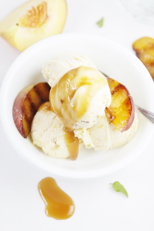 Grilled Peach Ice Cream with Caramel Sauce in white bowl. Peach slices in background.