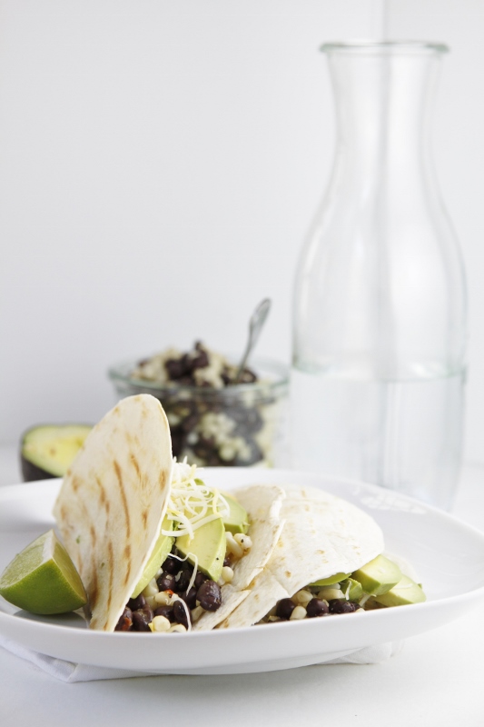 Black Bean and Avocado Grilled Tacos on white plate. Taco filling in glass jar in background with avocado.
