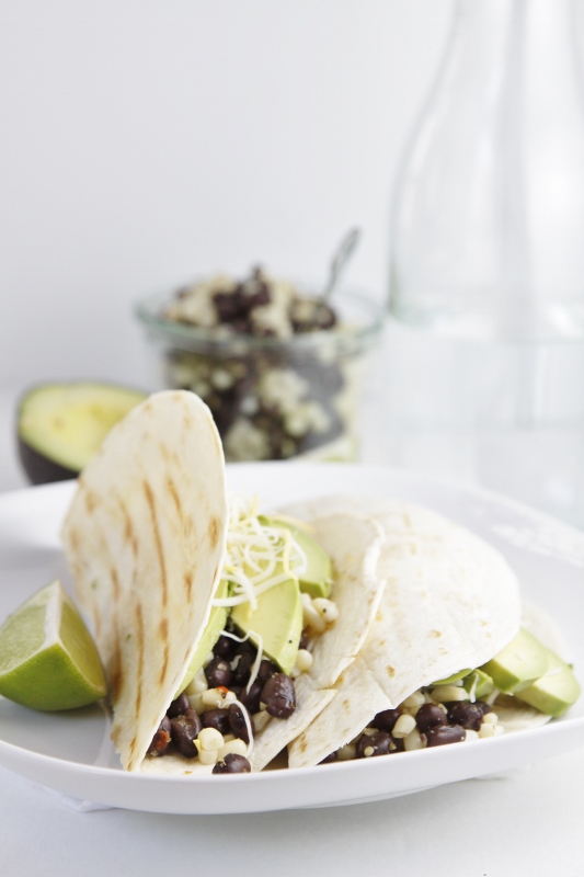 Black Bean and Avocado Grilled Tacos on white plate. Glass jar with extra filling in background with avocado.