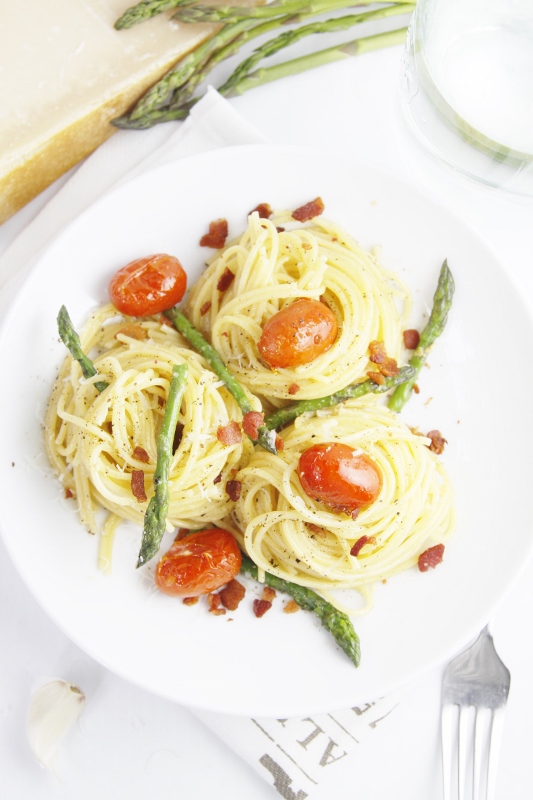 Asparagus and Tomato Carbonara in white bowl with fork.