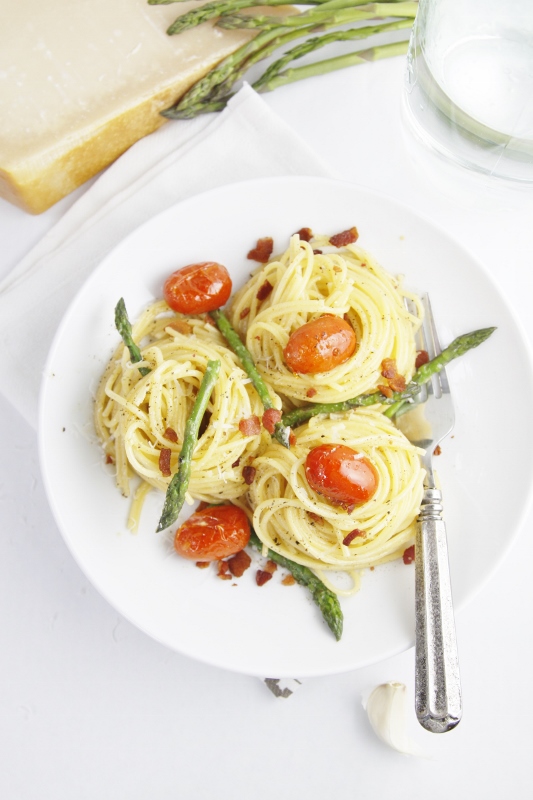 Asparagus and Tomato Carbonara pasta in white bowl with fork.