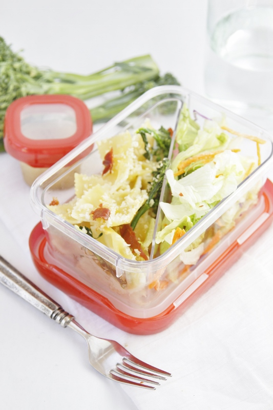 Cheesy Baked Pasta with Broccolini and salad packed in lunch container. Fork and salad dressing container to side.