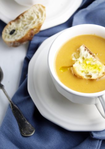 white cup of creamy roasted pumpkin soup.