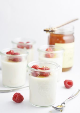 chai panna cotta in glass jars garnished with raspberries