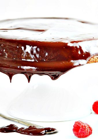 Chocolate Cake with Ganache on white cake plate with serving fork.