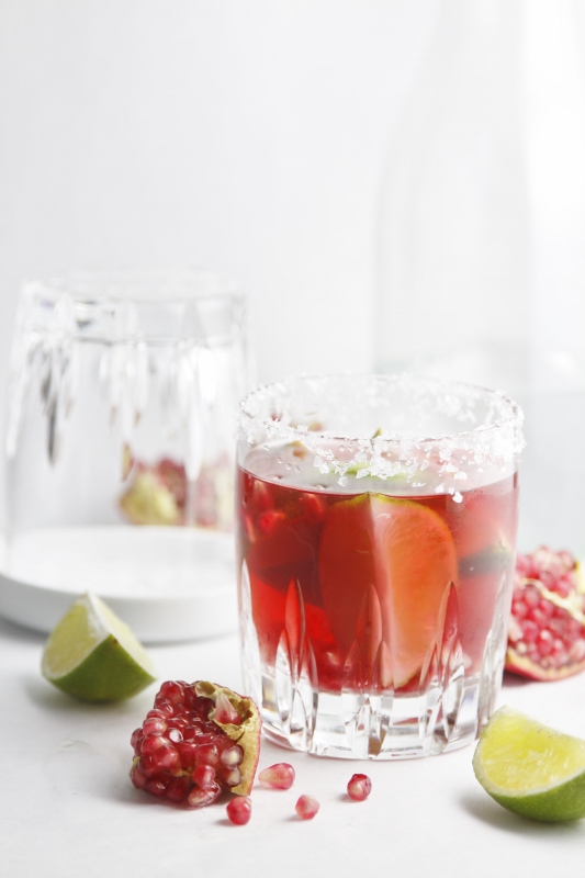 Pomegranate Lime Margarita with lime and pomegranates scattered around.