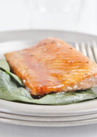 salmon filet with glaze on pewter plate with fork.