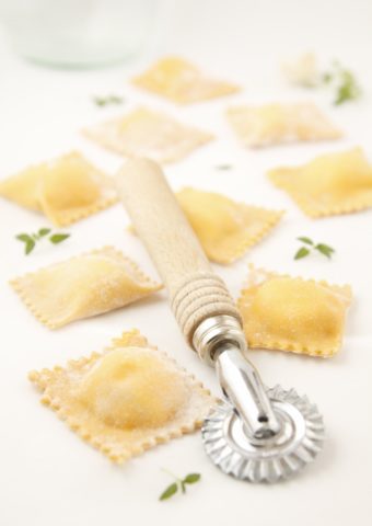 carrot ravioli scattered with pasta roller in center.