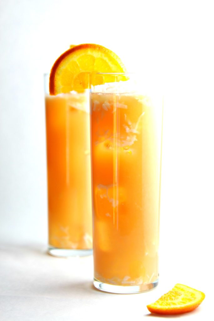 2 tall cocktails garnishes with orange wedges. 