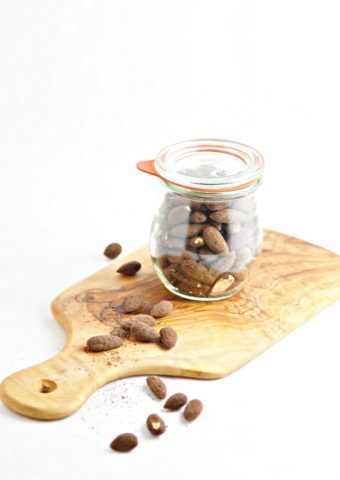 glass jar with espresso roasted almonds sitting on cutting board.