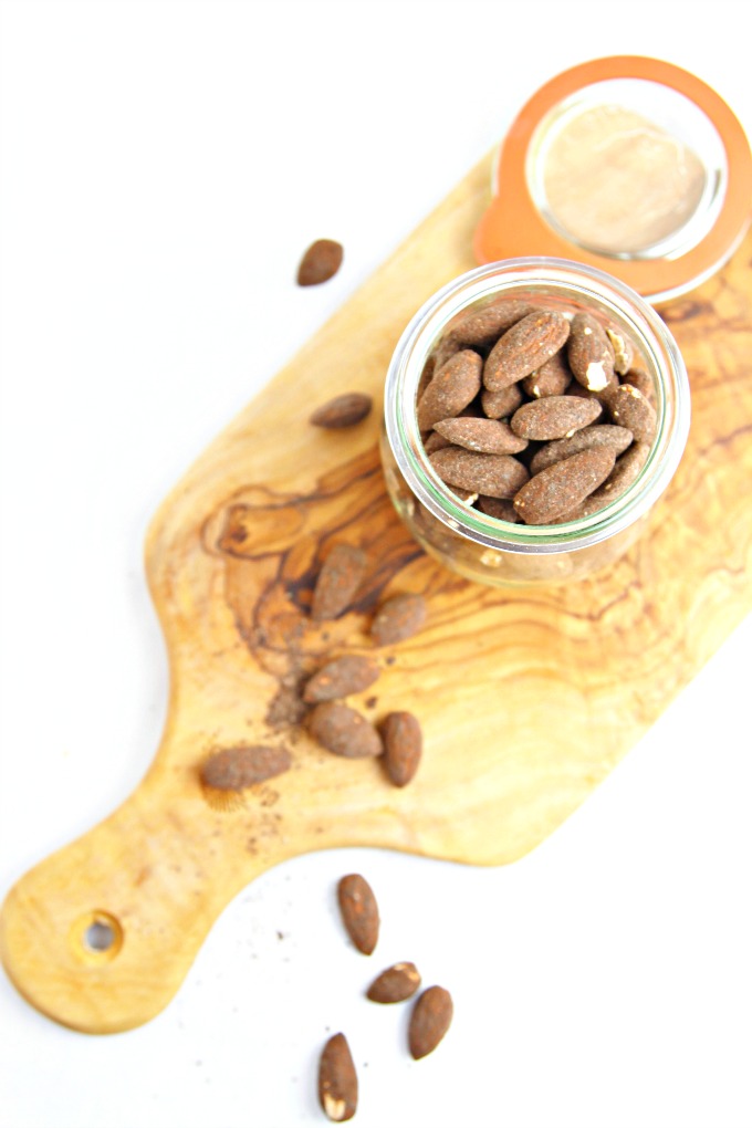 Spicy Dark Chocolate Espresso Roasted Almonds in glass jar on cutting board. 