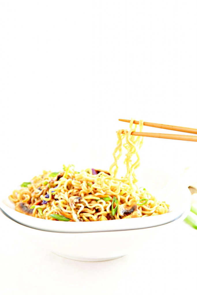 White bowl of Vegetable Ramen Noodles. Chopsticks pulling noodles upwards out of bowl. 