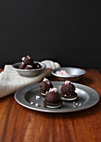 Peppermint OREO Cookie Balls on silver plate with bowl of crushed peppermints to side