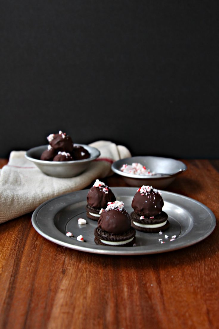 Peppermint OREO Cookie Balls on silver plate with bowl of crushed peppermints to side