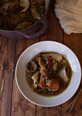 Chicken and Dumplings with Mushrooms in white bowl. Le Creuset of meal behind with dishtowel to side.