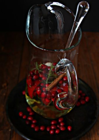 Christmas Sangria in white pitcher. Cranberries scattered around.