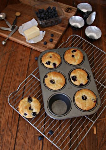 Blueberry Muffins in tin on cooling rack. Muffin ingredients behind.
