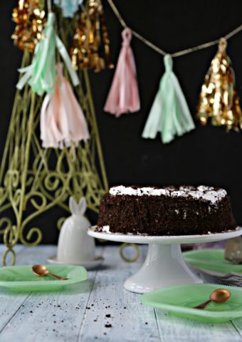 oreo ice cream cake on white cake stand with festive tassels and green plates surrounding