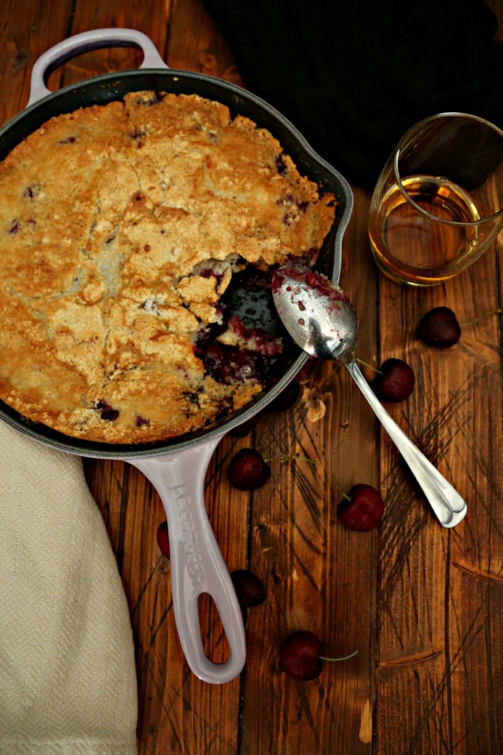 Cherry Cobbler in lavender skillet with spoon.