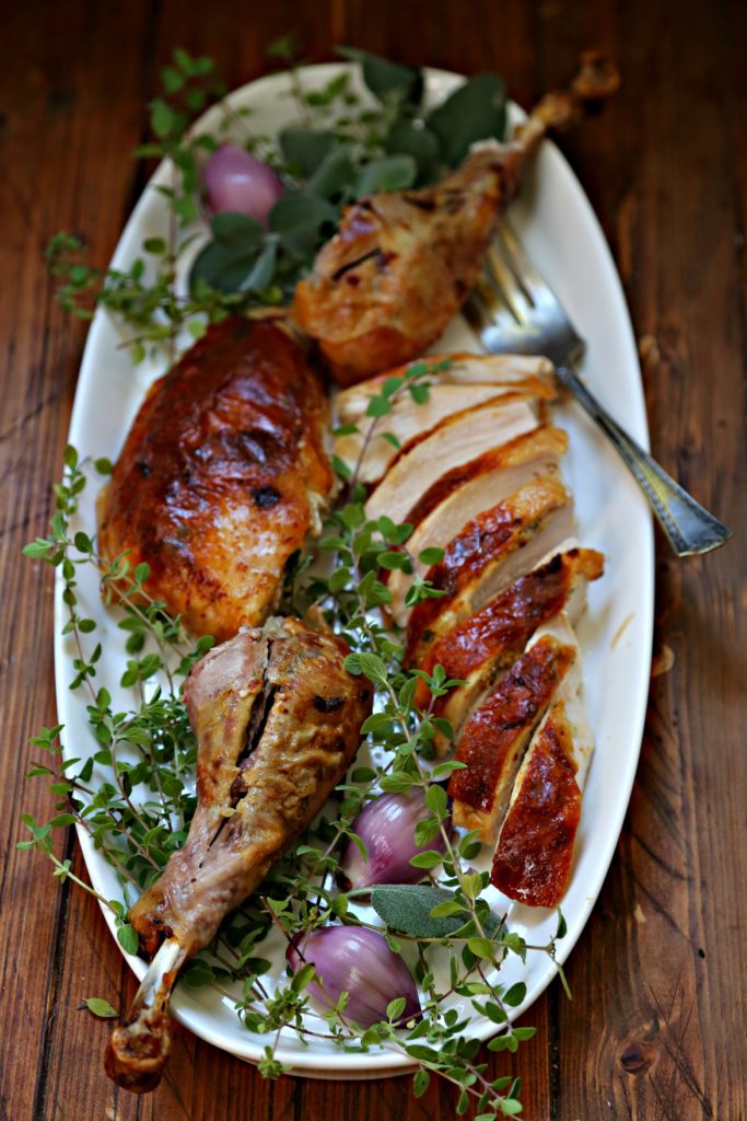 Mayonnaise Herb Roasted Turkey sliced on a plater with herbs and a serving fork
