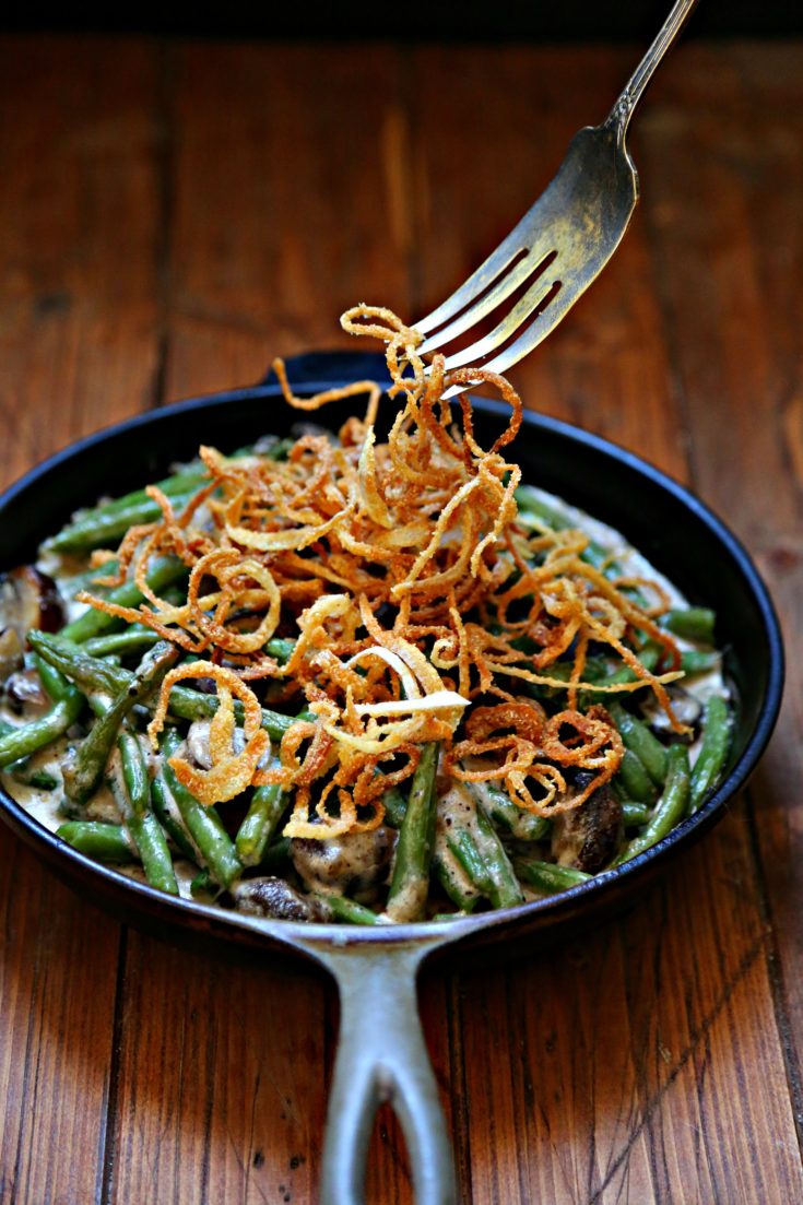 Fresh Green Bean Casserole in a skillet with Crispy Onions being pulled with fork