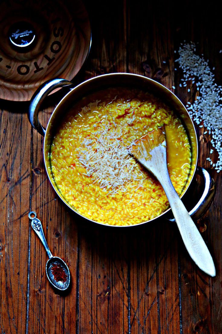 a pot of saffron risotto with risotto scattered around