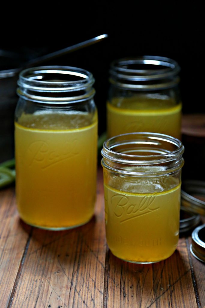 Easy Instant Pot Chicken Stock in glass jars with celery to side and strainer