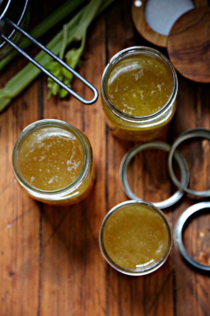 Easy Instant Pot Chicken Stock in glass jars with celery and strainer to side