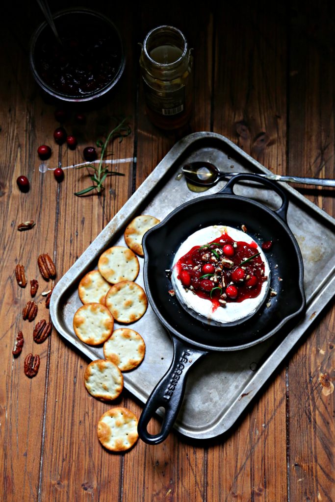 Cranberry Pecan Baked Brie in skillet surrounded by crackers 