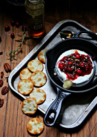 Cranberry Pecan Baked Brie in cast iron skillet surrounded by crackers